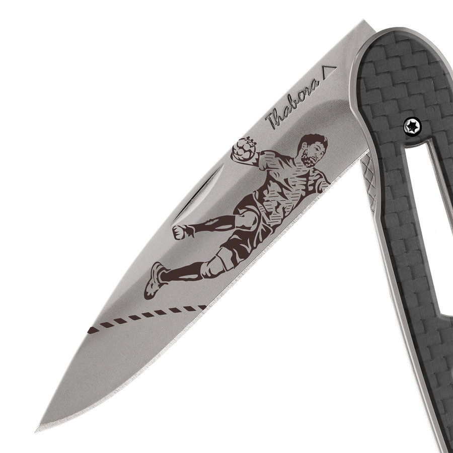 Couteau acier finition titane gris plaquette ajourée carbone motif «handball»