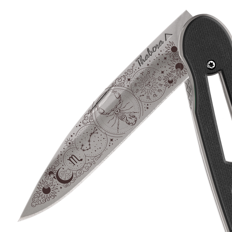 Couteau acier finition titane gris plaquette ajourée résine g10 noir motif «zodiaque scorpion»