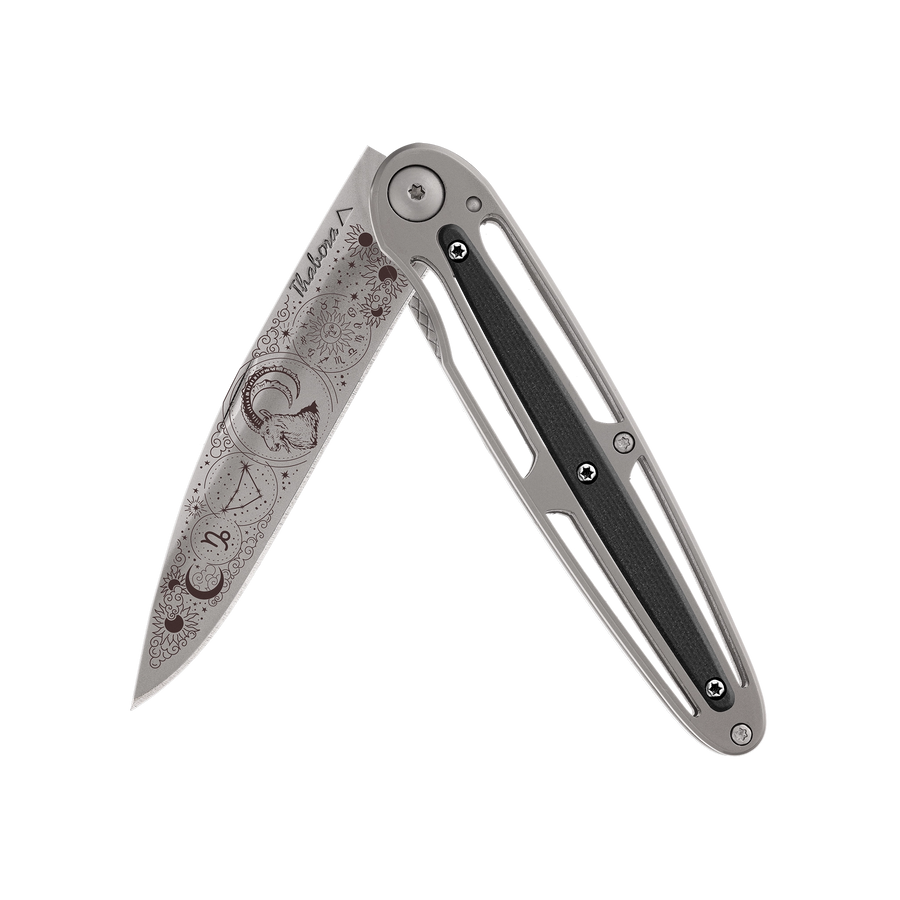 Couteau acier finition titane gris plaquette centrale résine g10 noir motif «zodiaque capricorne»