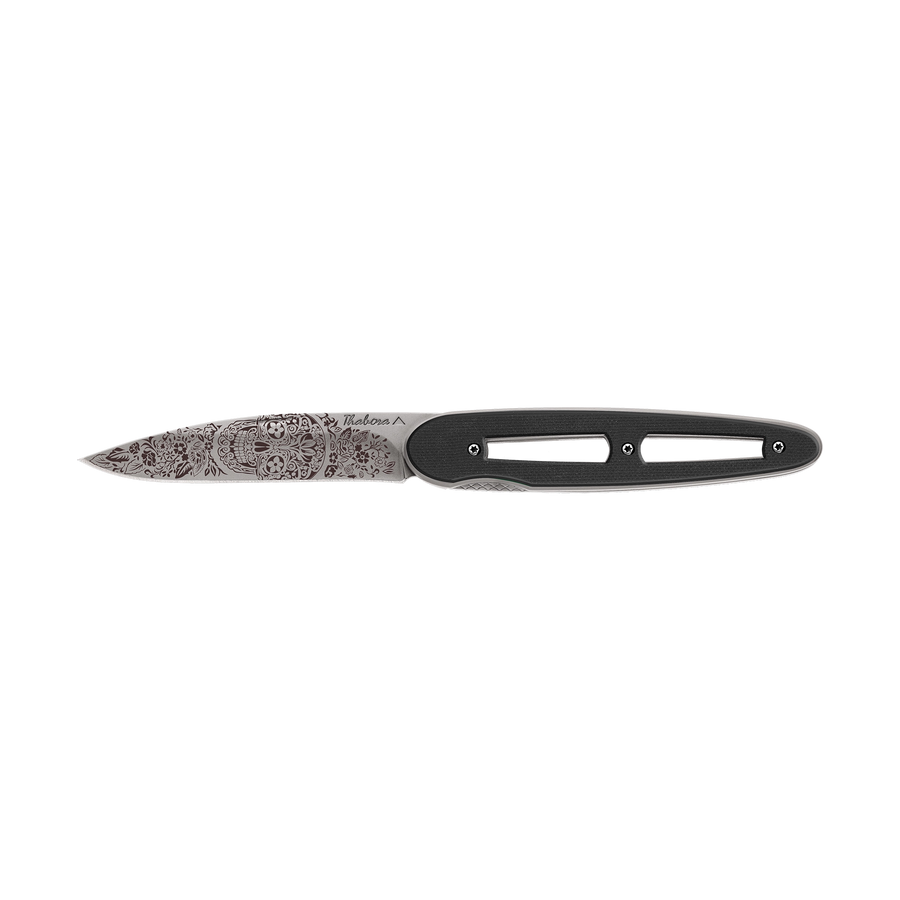 Couteau acier finition titane gris plaquette ajourée résine g10 noir motif «tête mexicaine»