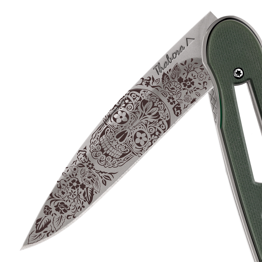 Couteau acier finition titane gris plaquette ajourée résine g10 kaki motif «tête mexicaine»