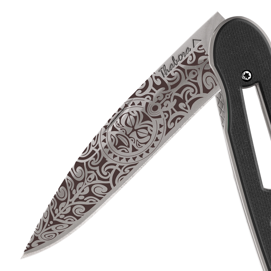 Couteau acier finition titane gris plaquette ajourée résine g10 noir motif «tiki»