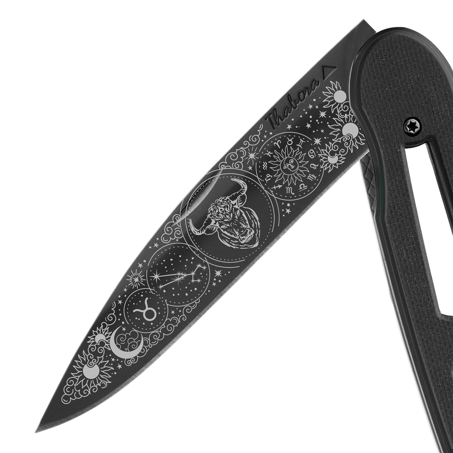 Couteau acier finition titane noir plaquette ajourée résine g10 noir motif «zodiaque taureau»
