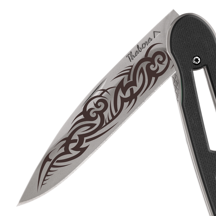 Couteau acier finition titane gris plaquette ajourée résine g10 noir motif «tribal gothique»