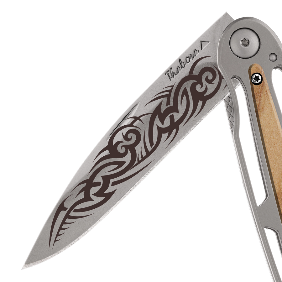 Couteau acier finition titane gris plaquette centrale bois clair motif «tribal gothique»