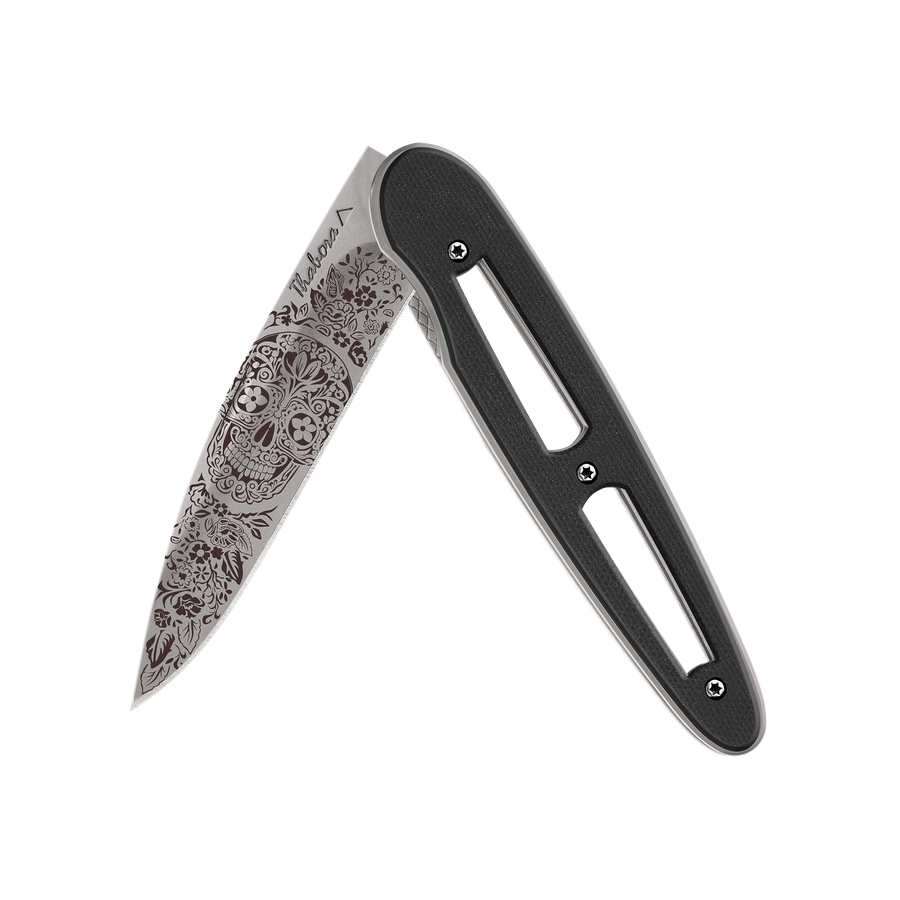 Couteau acier finition titane gris plaquette ajourée résine g10 noir motif «tête mexicaine»