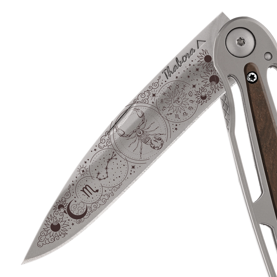 Couteau acier finition titane gris plaquette centrale bois foncé motif «zodiaque scorpion»