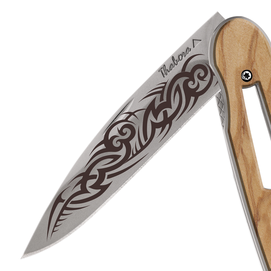 Couteau acier finition titane gris plaquette ajourée bois clair motif «tribal gothique»
