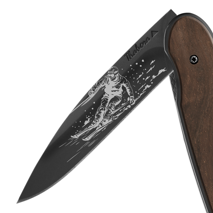 Couteau acier finition titane noir plaquette pleine bois foncé motif «skieur»